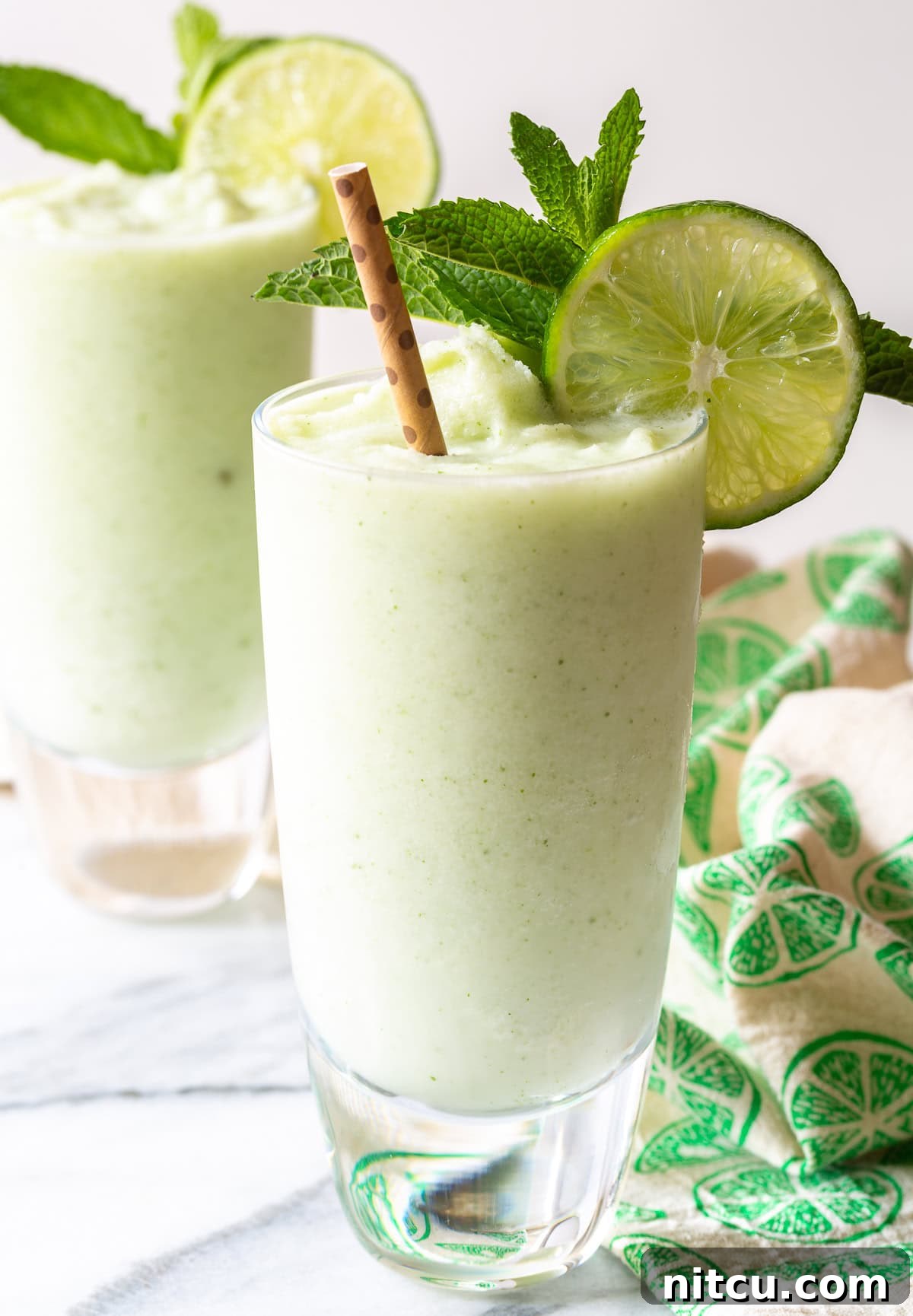 Creamy Frozen Coconut Mojito cocktail in a glass with mint and lime garnish