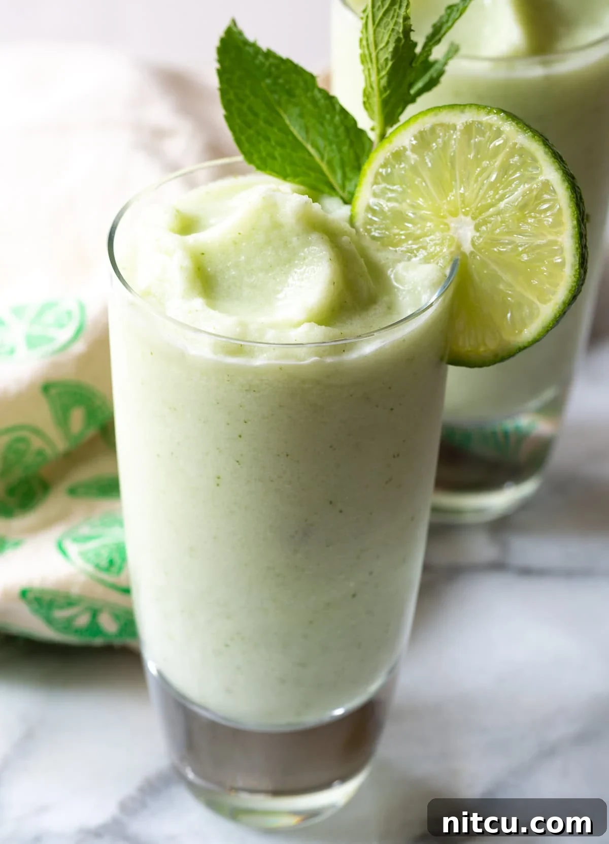 Close-up of a garnished Frozen Coconut Mojito glass