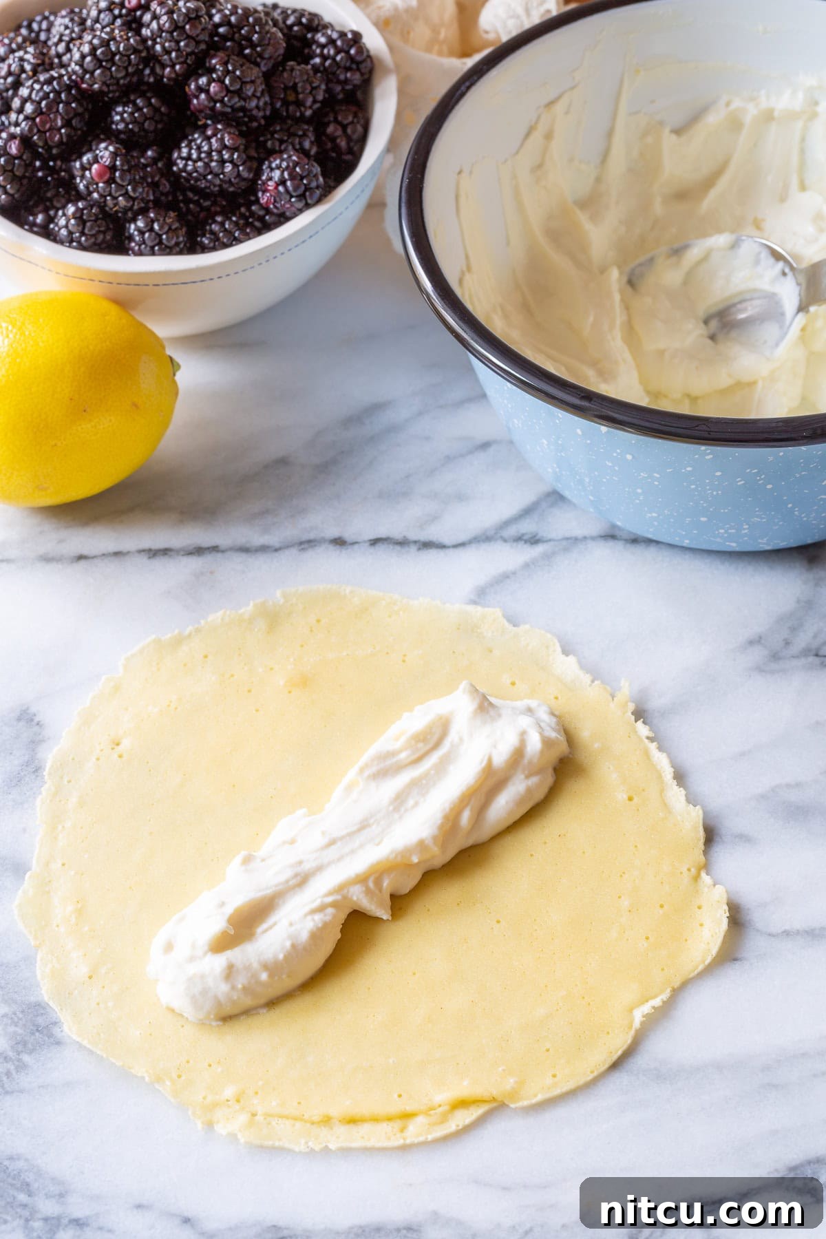 Spreading sweet ricotta cream evenly over a freshly cooked blini pancake