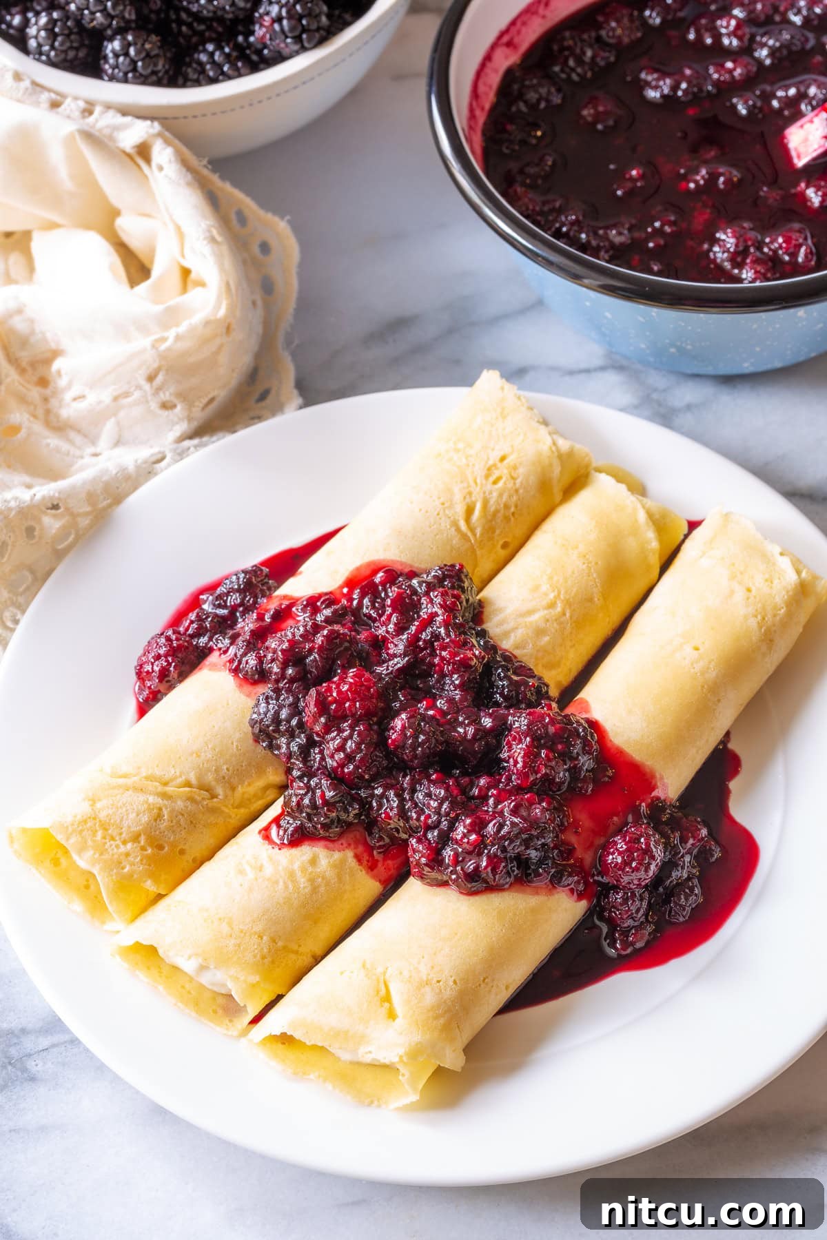 Drizzling warm, rich blackberry sauce over freshly prepared blintz pancakes