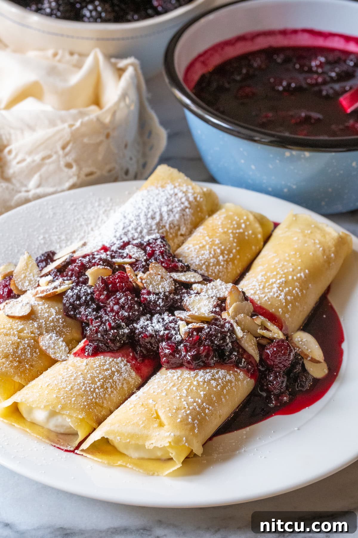 Blintz pancakes served beautifully with blackberry sauce and sliced almonds, ready to enjoy