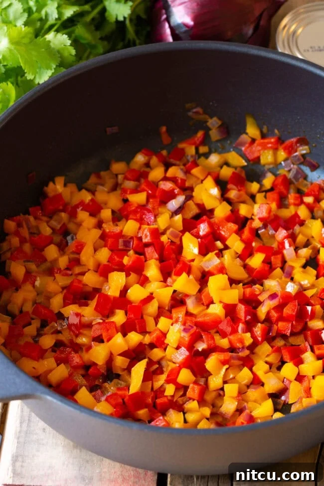 Diced vegetables being sautéed in a pan. 