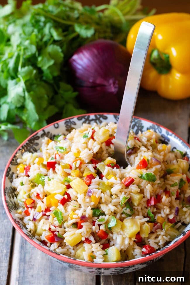 Zesty Caribbean Confetti Rice Recipe in bowl with a large serving spoon. 
