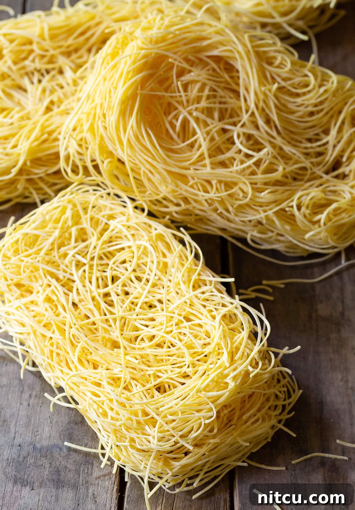 A vibrant pile of uncooked egg noodles, perfectly prepared for making a delicious batch of Lo Mein.