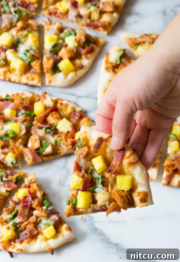 Chicken Teriyaki Pizza - lifting a piece with a hand, showing the crispy crust and melted cheese.