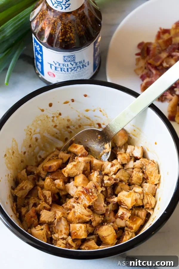 Bowl full of chopped, grilled chicken being marinaded in teriyaki sauce, ready for pizza.