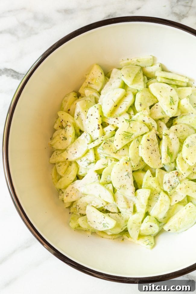 A large bowl of vibrant creamy cucumber dill salad, beautifully presented and ready to be served at a summer potluck or family dinner.