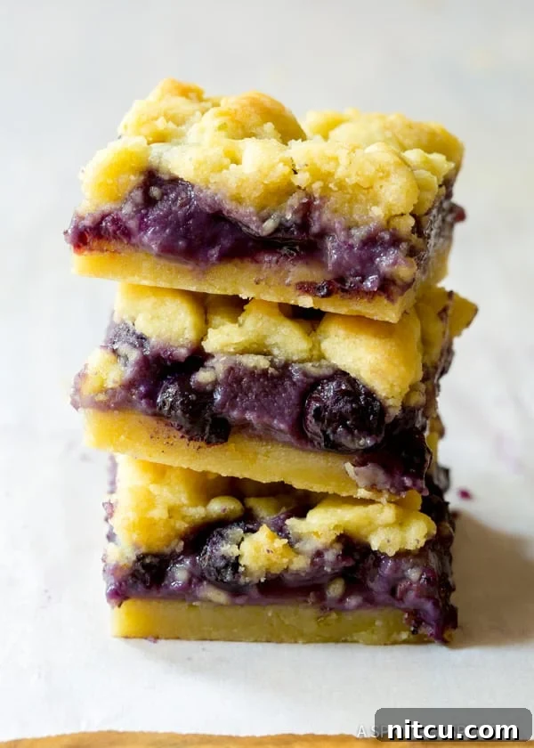 Three Blueberry Bars stacked on top of each other, showcasing their layers and delicious texture.