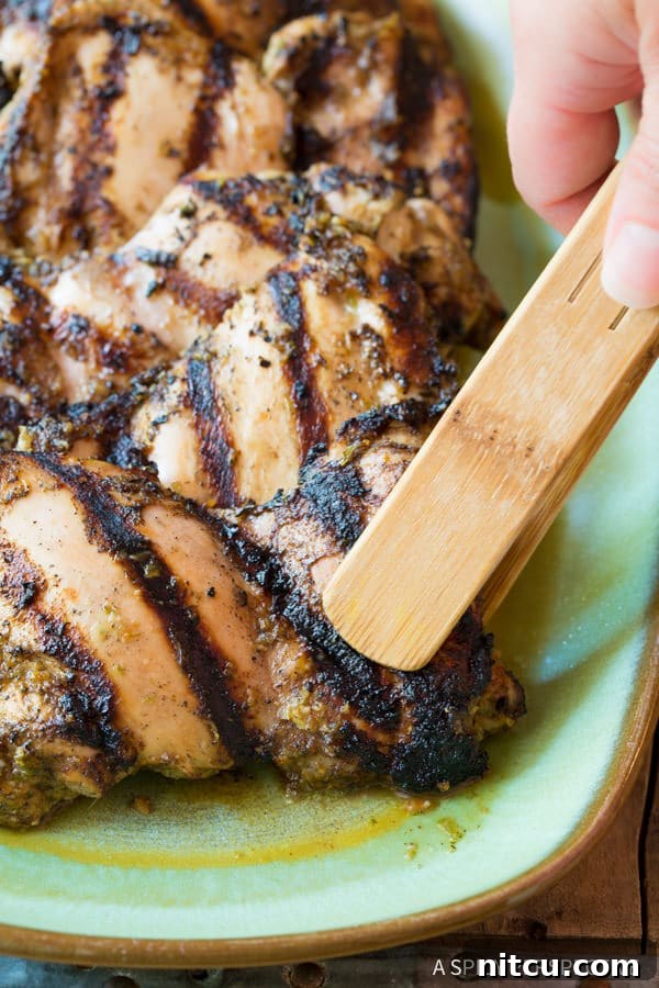 Jerk Chicken Thighs being picked up with tongs from the grill