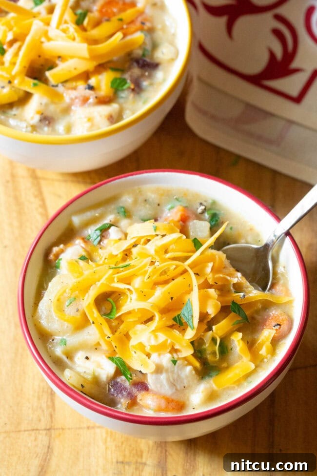 Two bowls of chicken potato soup topped with shredded cheese.