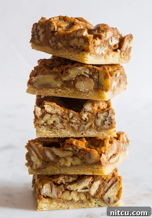 Pecan Pie bars stacked on top of each other, showcasing their inviting layers.