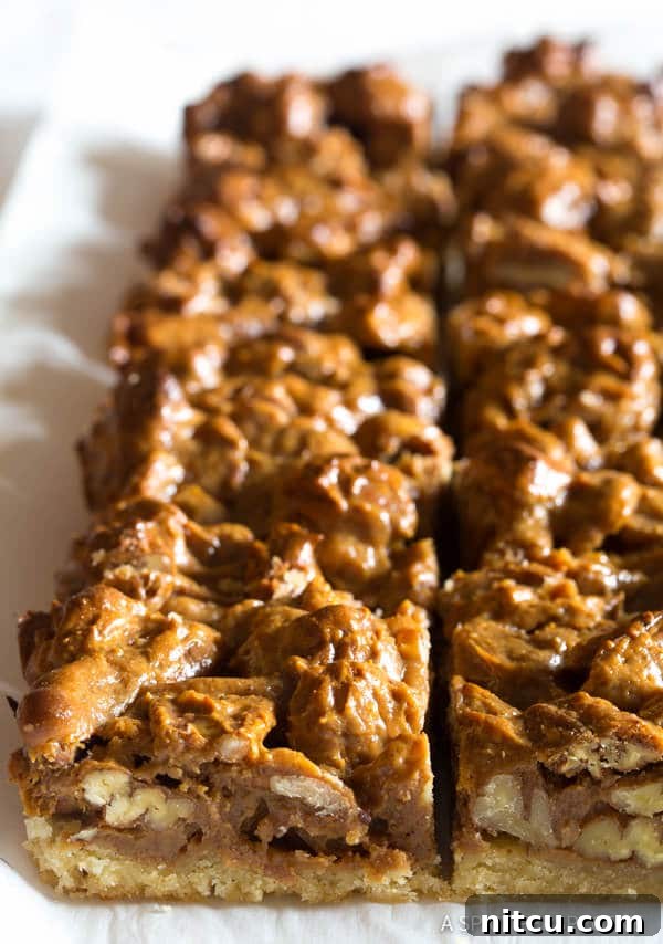 Caramel pecan slab pie meticulously arranged on parchment paper, expertly cut into uniform bars.