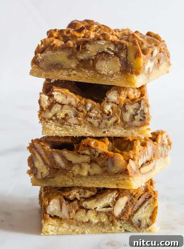 Pecan pie bars stacked to reveal their beautiful layers and textures, a perfect holiday dessert.