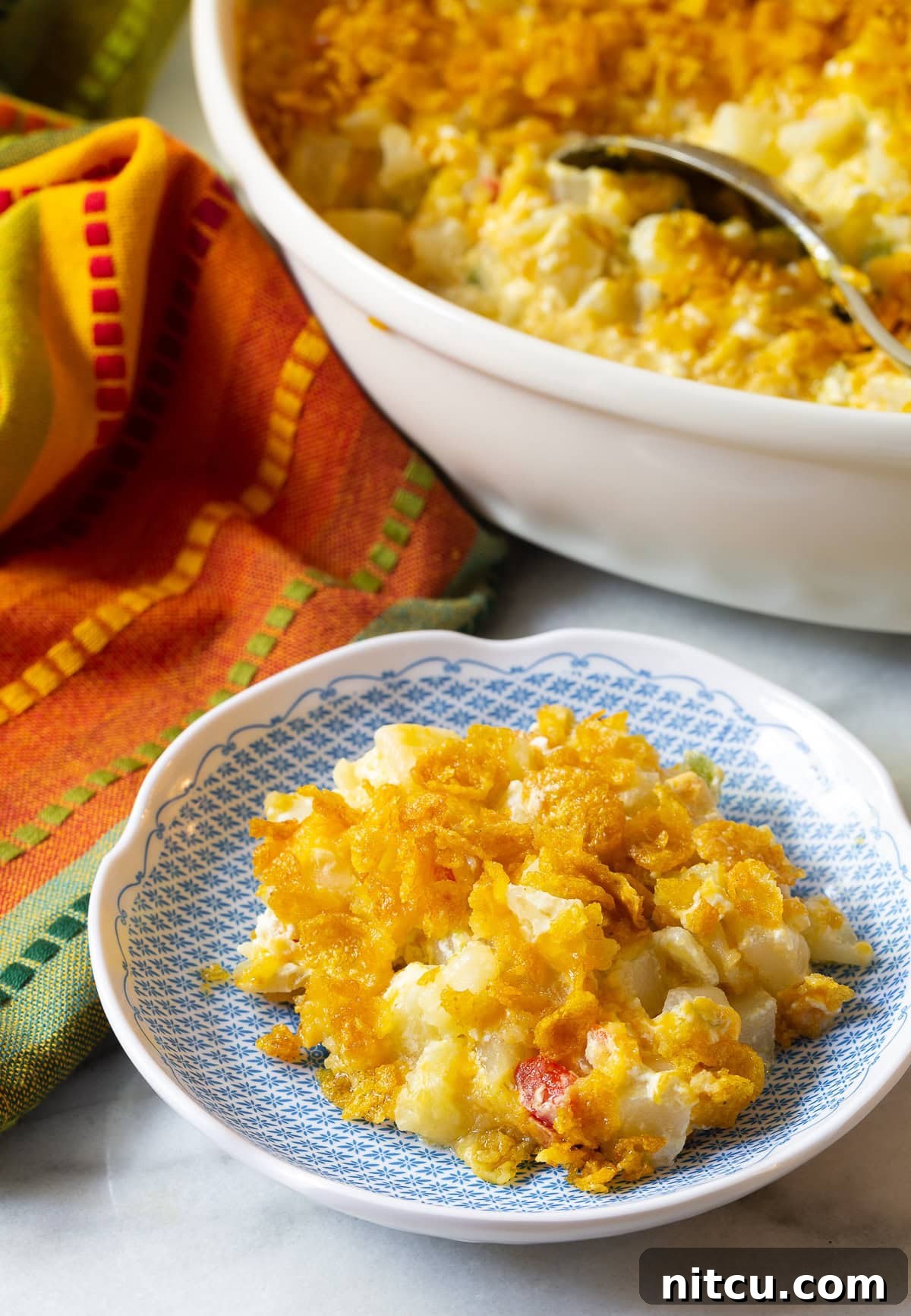 Plated company potato with casserole dish and spoon in background. 