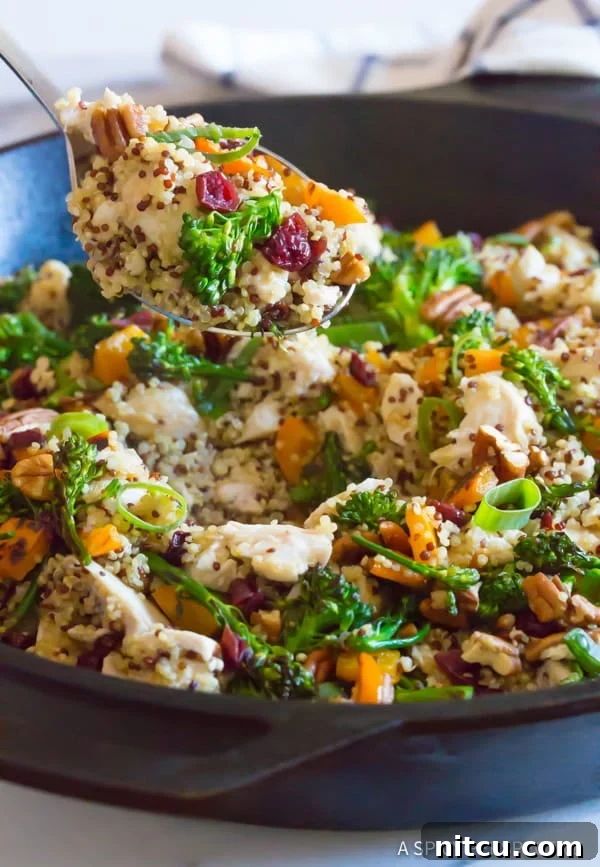 Lifting a portion of the finished Chicken and Quinoa out of the pan, demonstrating the rich, fluffy texture and inviting aroma of this healthy one-pot meal.