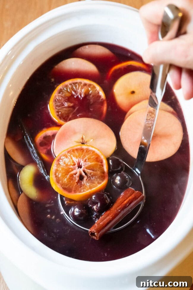 Mulled Wine (Hot Wassail Recipe) in a large crock with fruit floating on the top