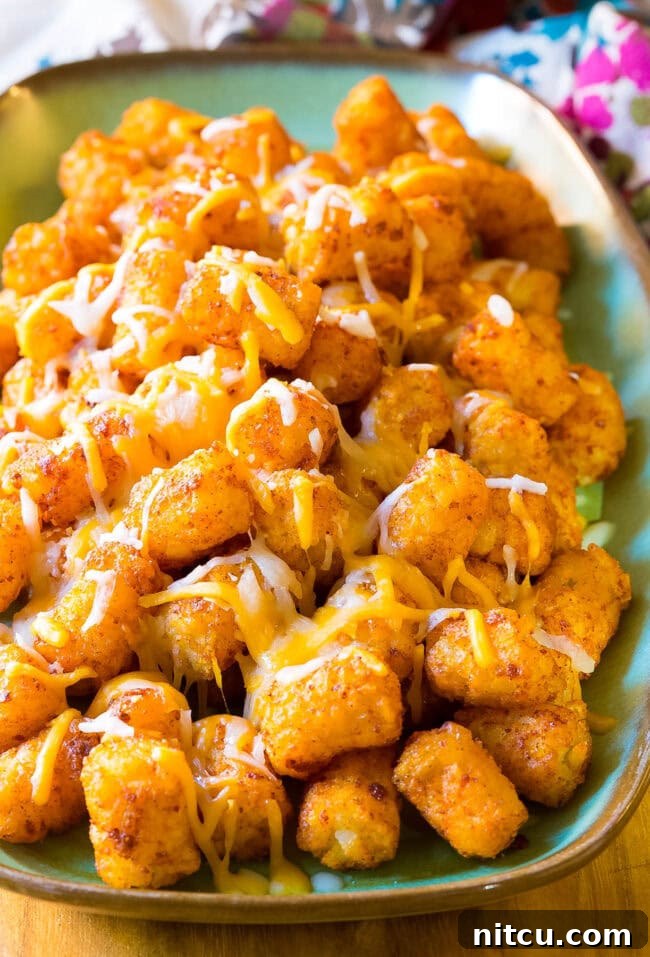 Tater tots topped with melted cheese on a serving platter. 