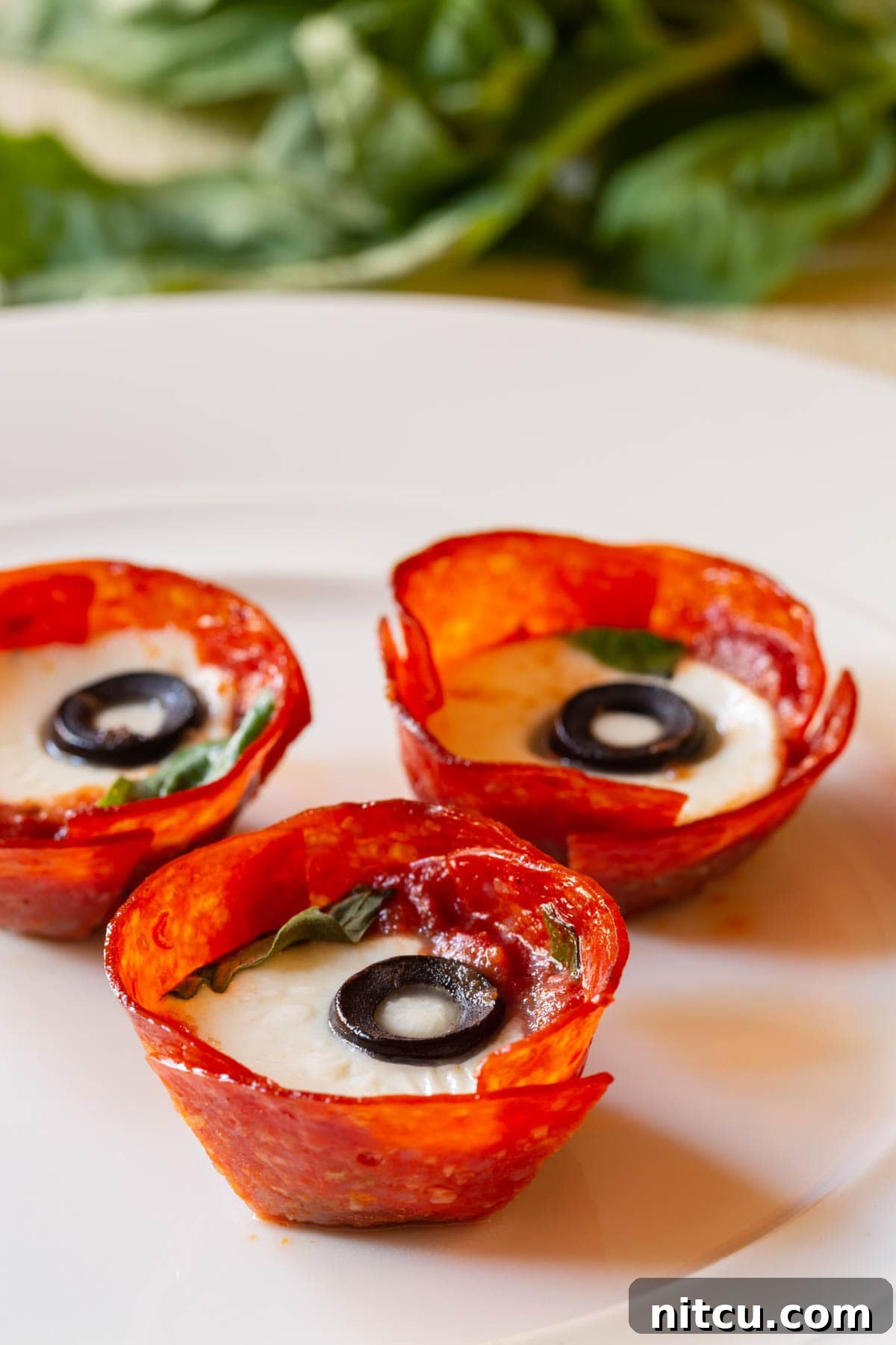 A mouth-watering close-up of a perfectly plated pepperoni cup, revealing its luscious melted cheese and crisp texture, garnished with fresh basil.