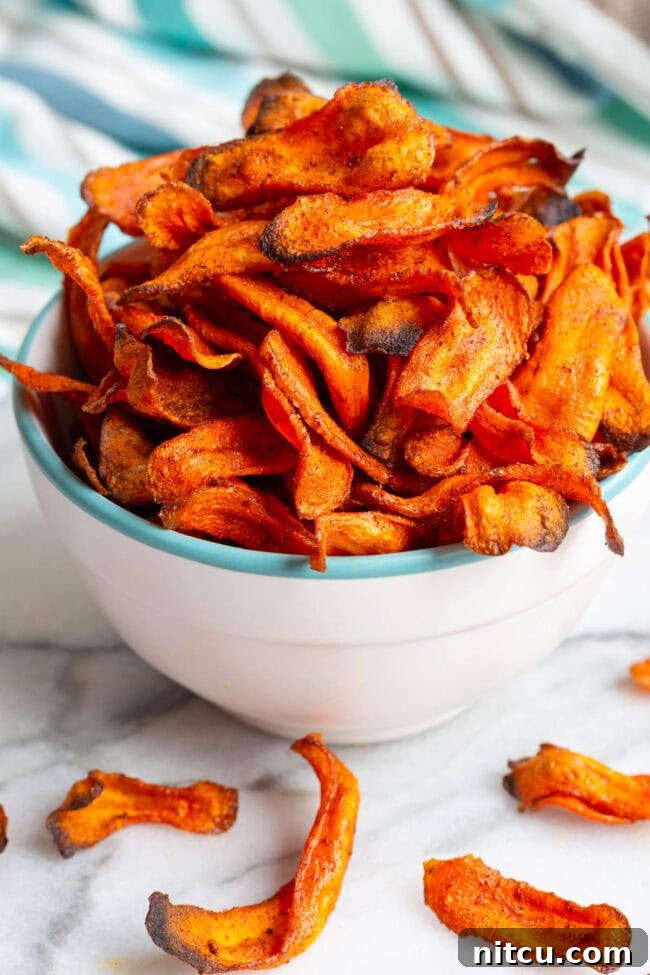 Perfectly baked carrot chips stacked in a vibrant bowl.