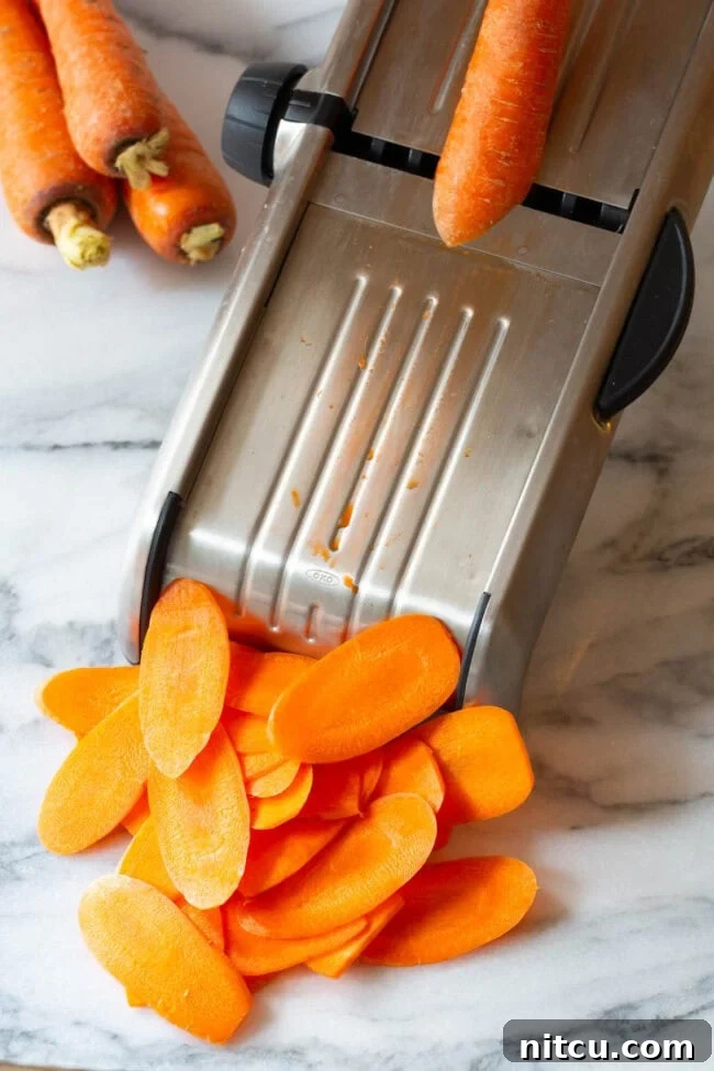 Carrots being expertly sliced by a mandolin for thin chips.