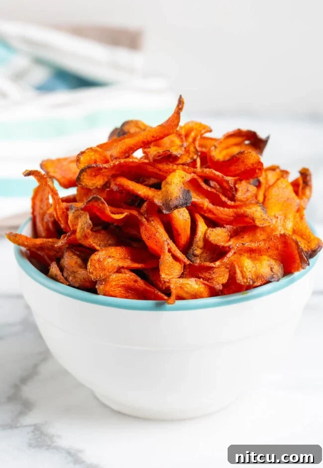 A bowl of delicious and healthy baked carrot chips, ready to be enjoyed as a snack.