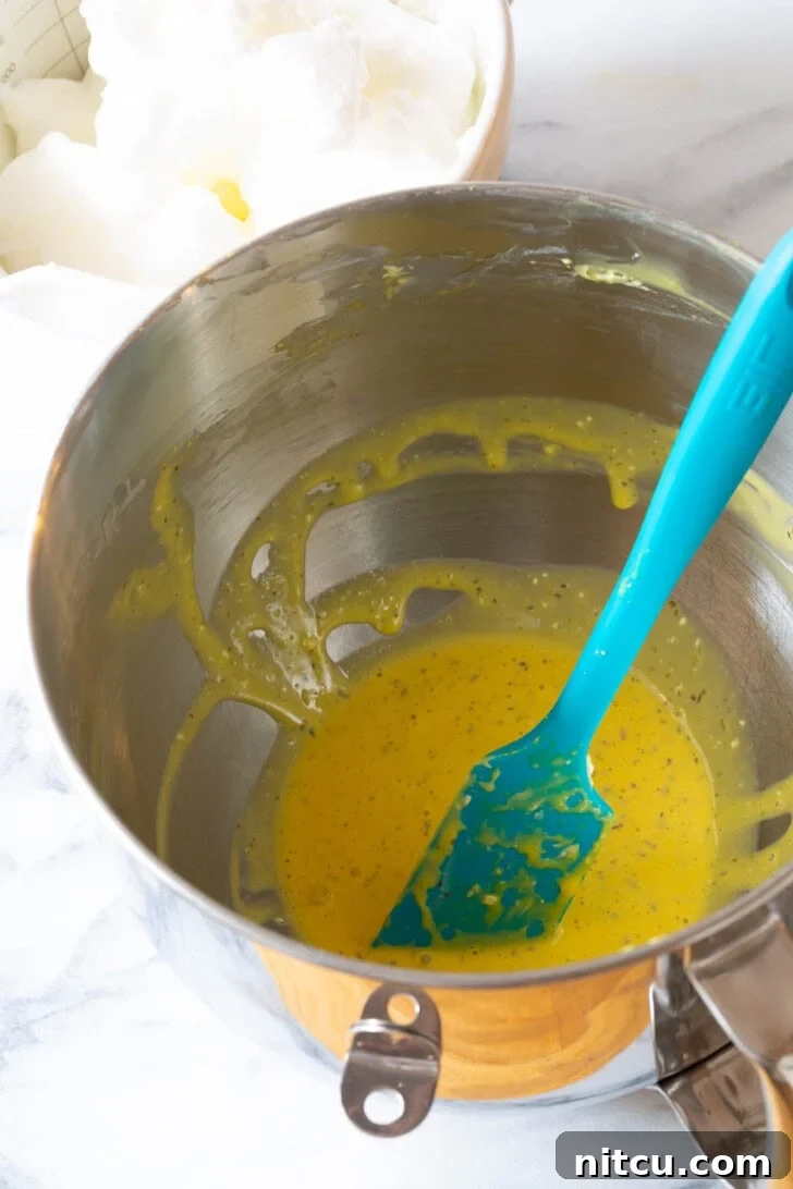 A stand mixer bowl filled with whipped egg yolks, beautifully blended with Italian seasoning, ready for the next step.