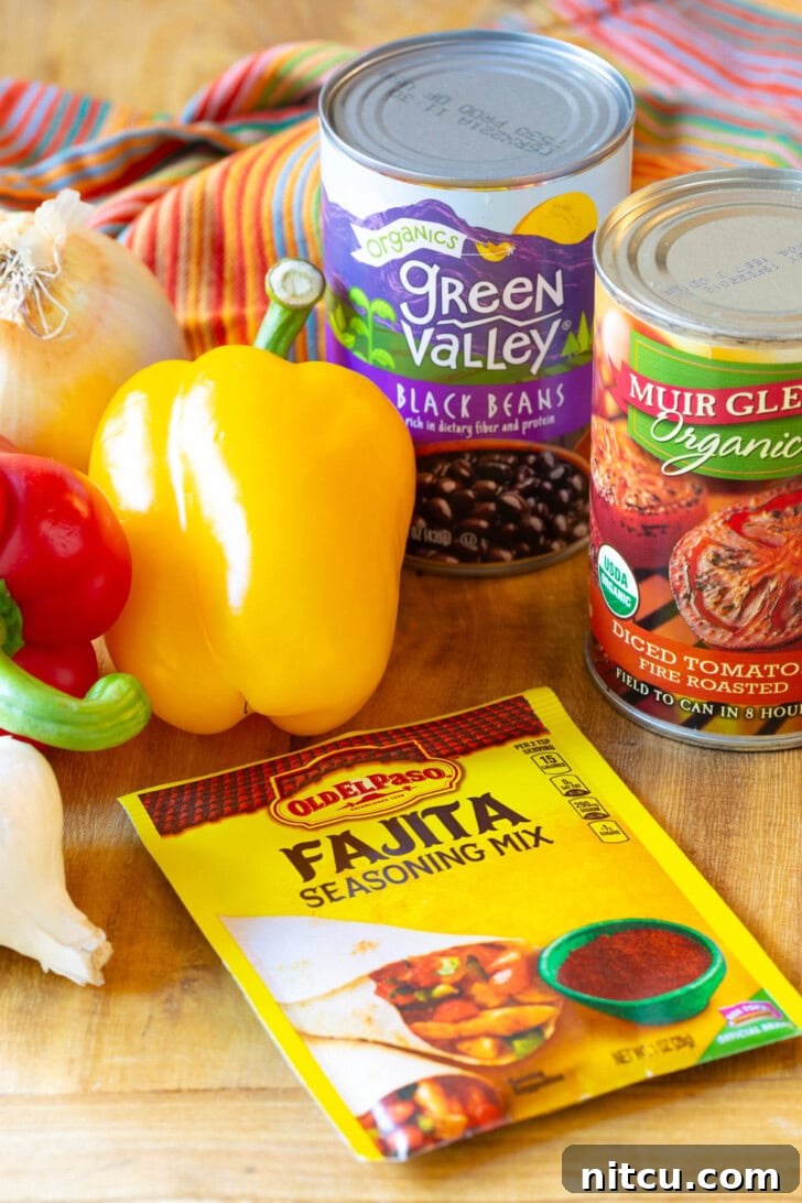 Ingredients for Mexican Chicken Soup laid out on a wooden cutting board: A packet of fajita seasoning mix, vibrant yellow and red bell peppers, a can of diced tomatoes, a can of black beans, and a bulb of garlic.