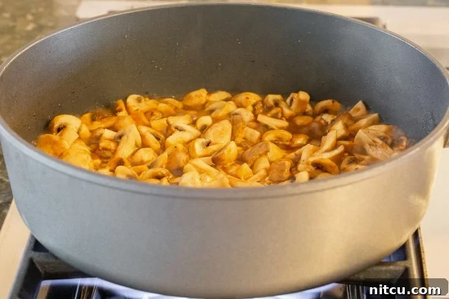 Mushrooms and sauce cooking in a skillet.