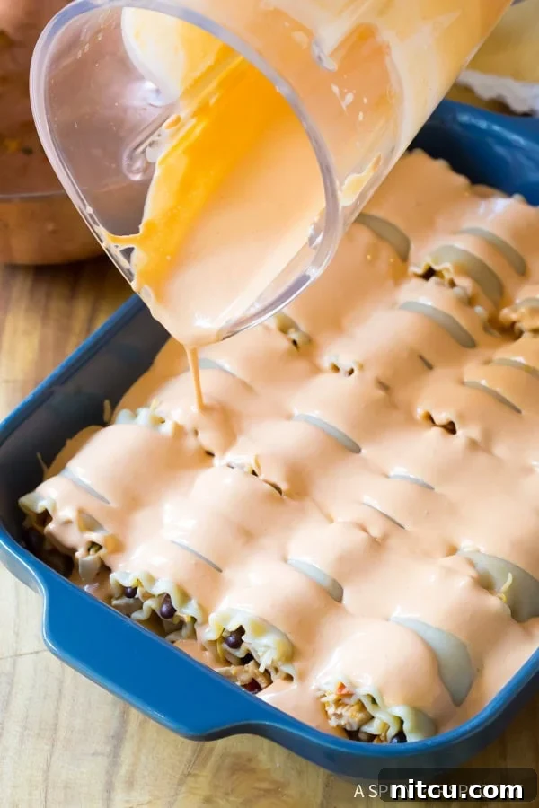 A hand spreading the chicken and bean filling onto a cooked lasagna noodle.