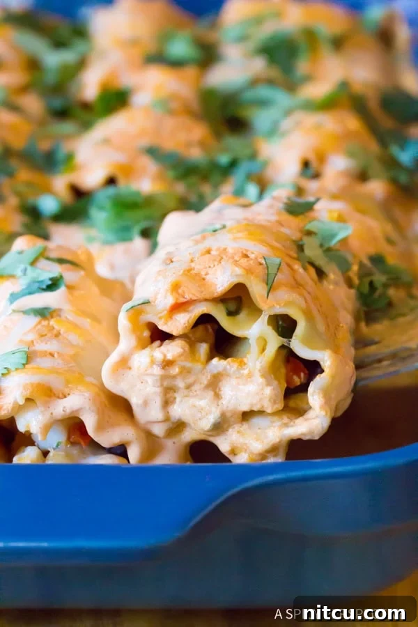 Cheesy Southwest Chicken Lasagna Rolls in a baking dish, covered with sauce before baking.