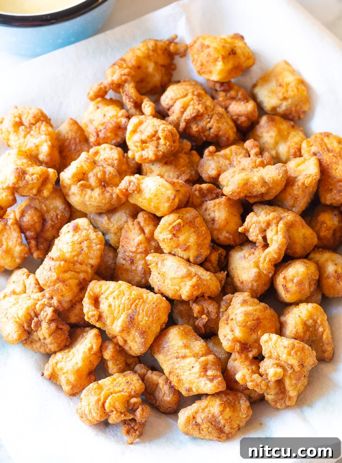 Freshly fried Chick-fil-A style nuggets resting on a paper towel-lined plate to drain excess oil.