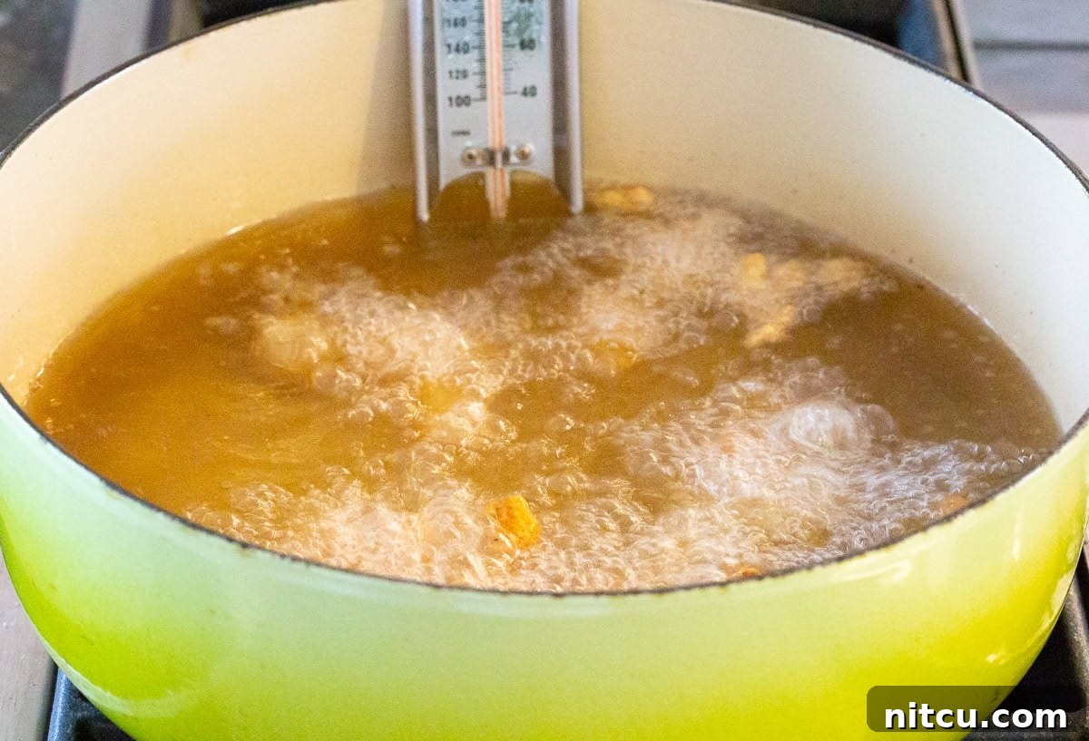 A pot of hot oil with several chicken nuggets frying until golden brown.