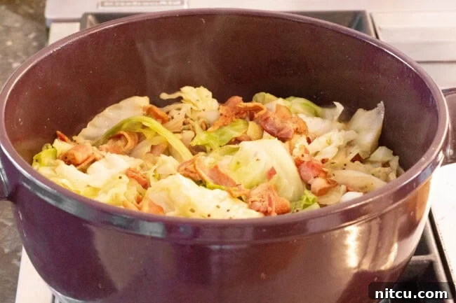A large pot of cooked bacon and cabbage resting on the stove after simmering.