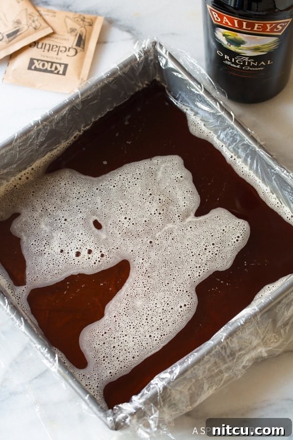Hot coffee mixture poured into a square baking dish lined with plastic wrap, setting the foundation for the jello shots.