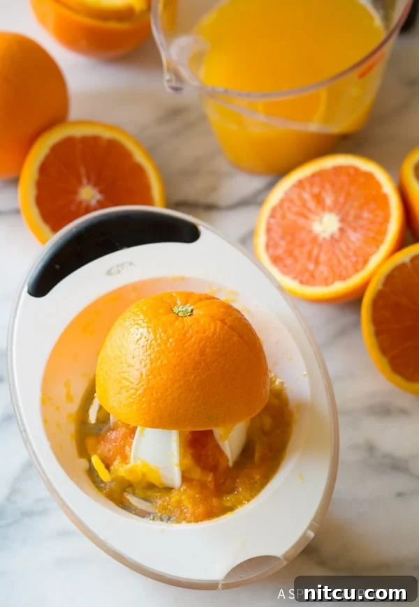 Close-up view of fresh oranges being expertly juiced to extract their vibrant liquid, emphasizing the importance of fresh ingredients for a homemade Southern orangeade.