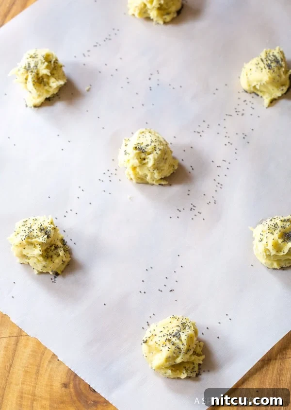 Cookie dough balls neatly arranged on a baking sheet lined with parchment paper, ready for the oven.