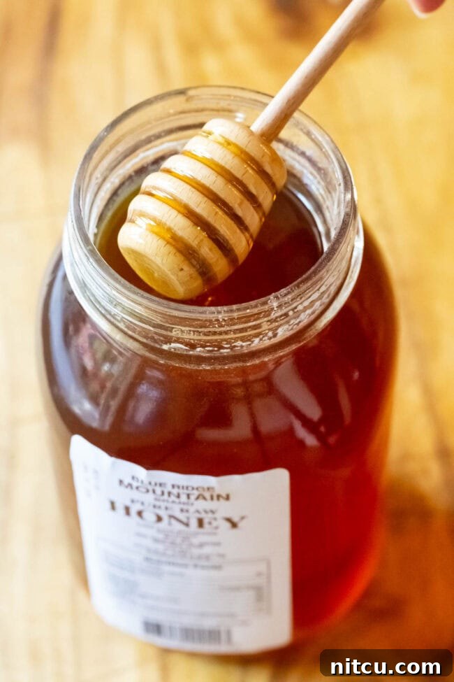 A close-up shot of rich, golden honey, ready to be added to the lemon ginger tea for natural sweetness.