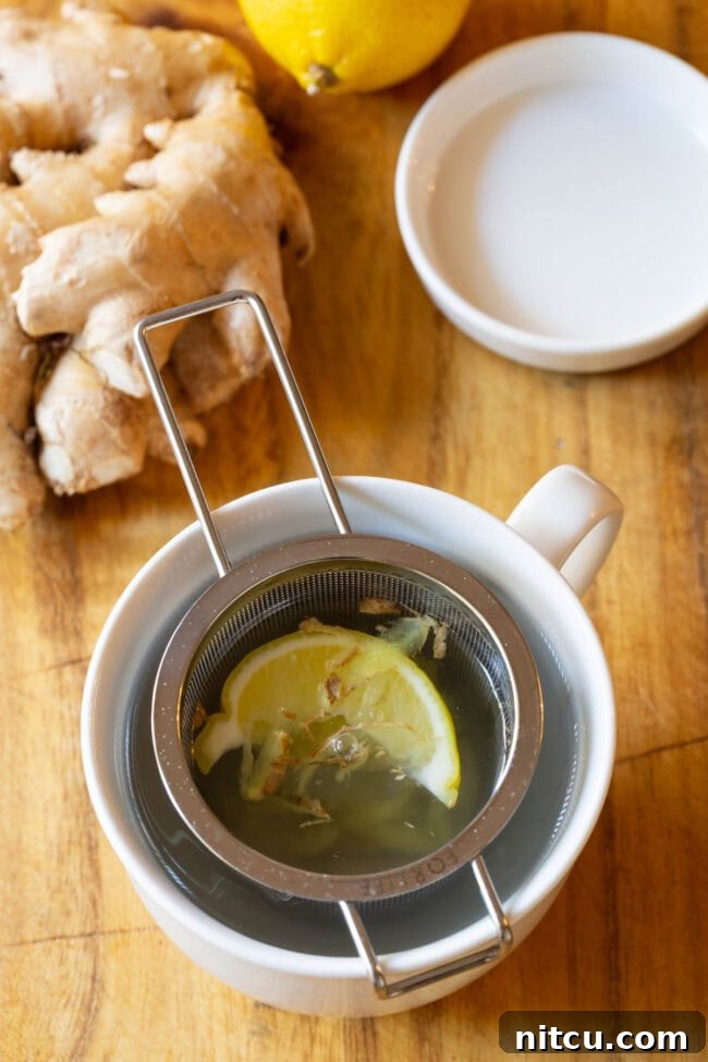 A comforting mug of Lemon Ginger Detox Tea with a tea infuser, ready to be enjoyed.