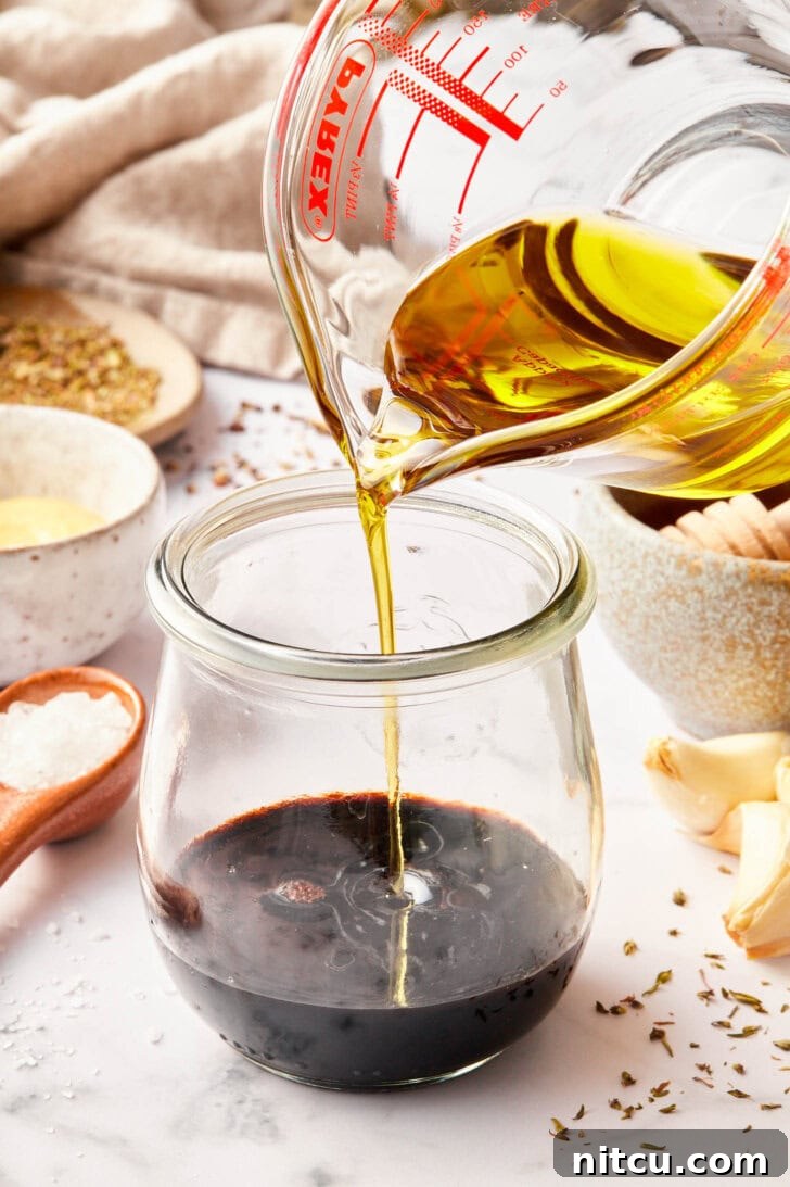 balsamic vinaigrette recipe in jar with oil being added