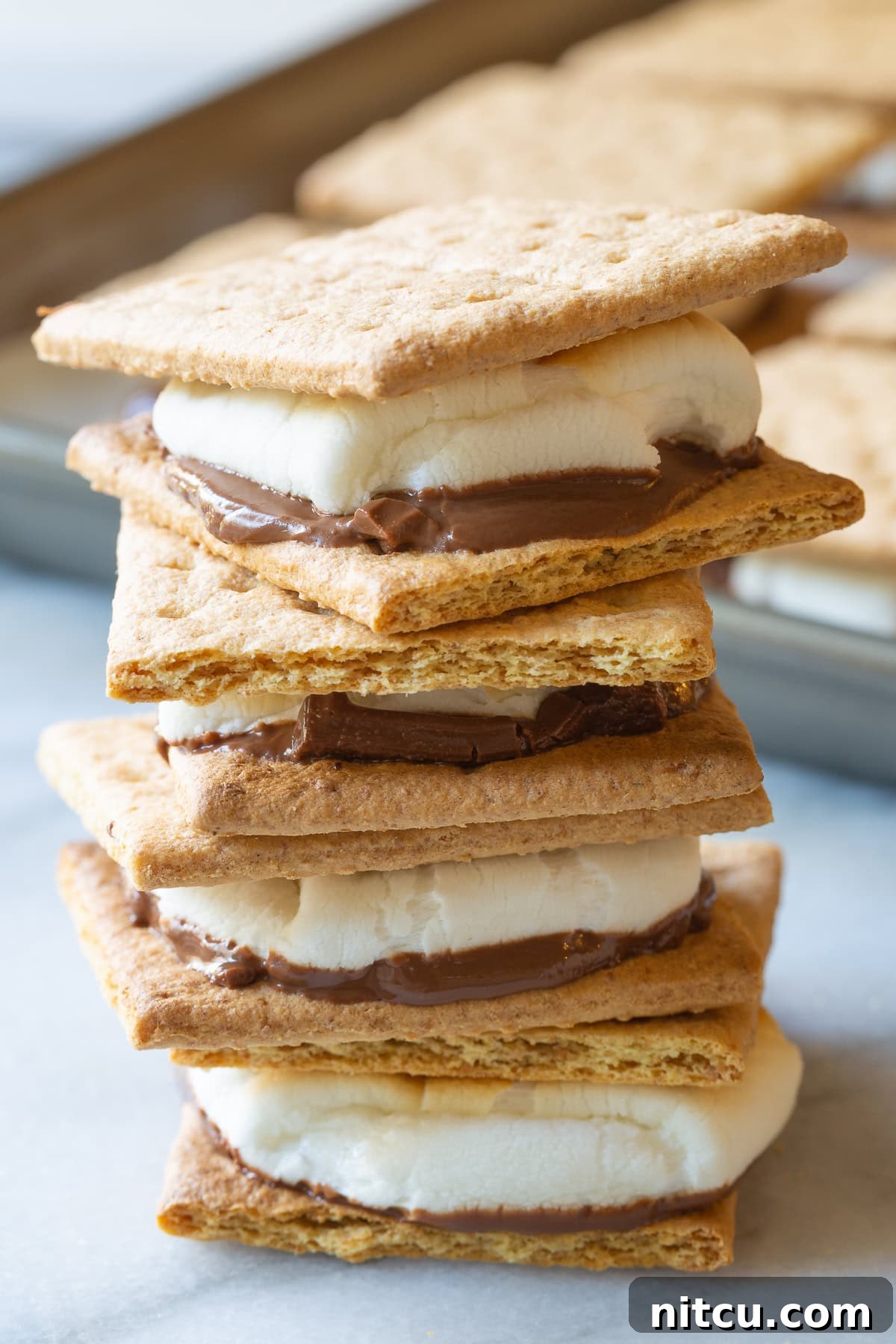 How To Make Smores In The Oven - Baked s'mores sandwiches stacked on top of each other. 