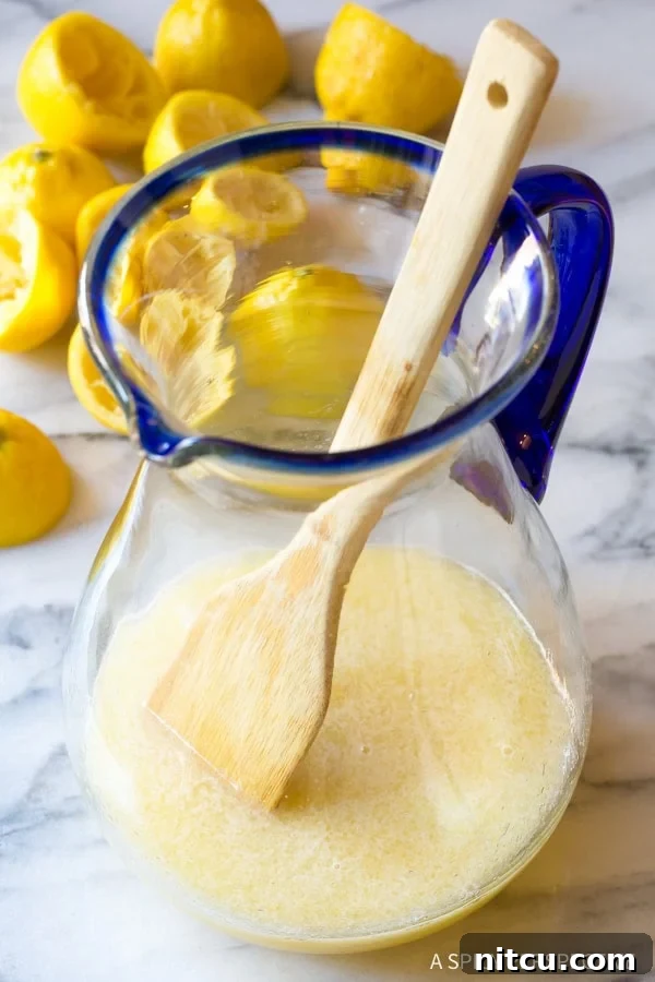 A wooden spoon actively mixing the lemon juice, stevia, and water together in a pitcher to fully combine the ingredients.