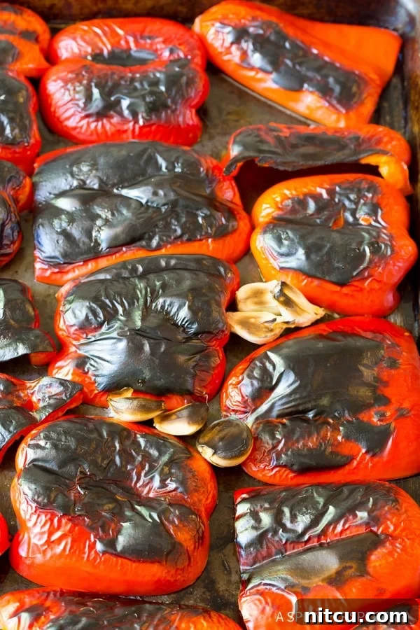 Red bell peppers on a baking sheet after being roasted. 