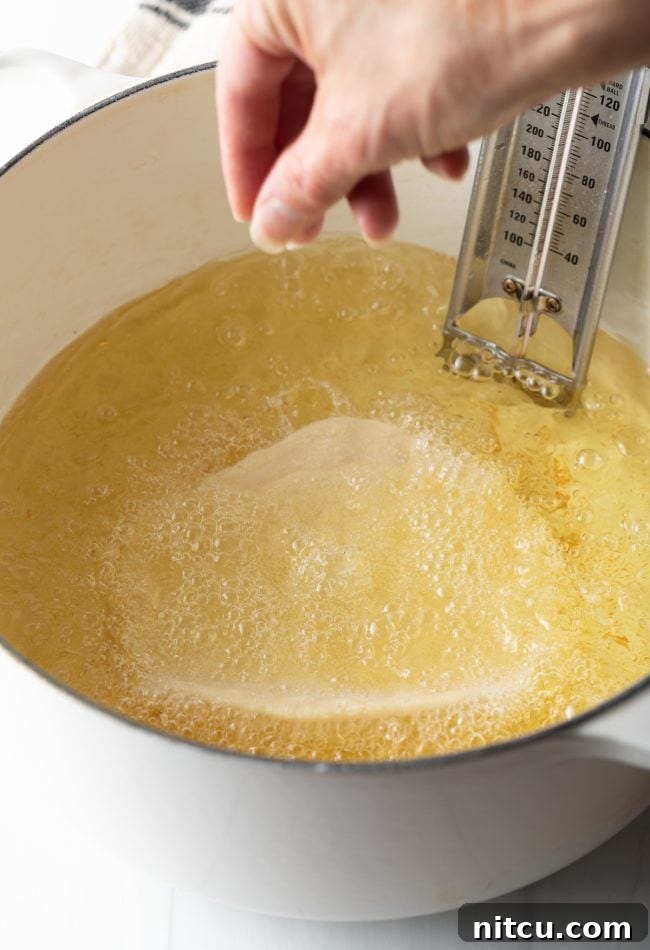 A piece of Navajo fry bread actively frying in hot oil within a large Dutch oven, showing the bubbling oil and the dough beginning to puff.