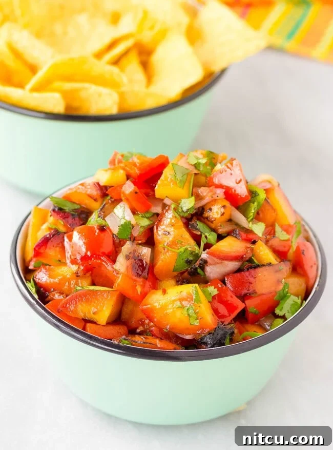 Bowl of grilled chipotle peach salsa served with a bowl of chips, ready for a delicious snack or appetizer.