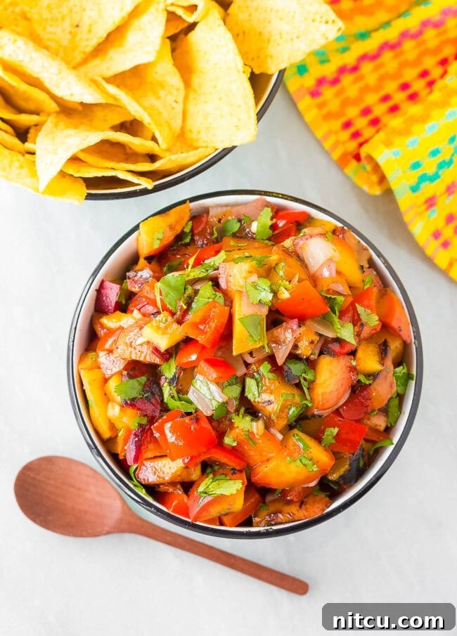 Top down view of a colorful bowl filled with fresh grilled peach salsa, showcasing its vibrant ingredients.