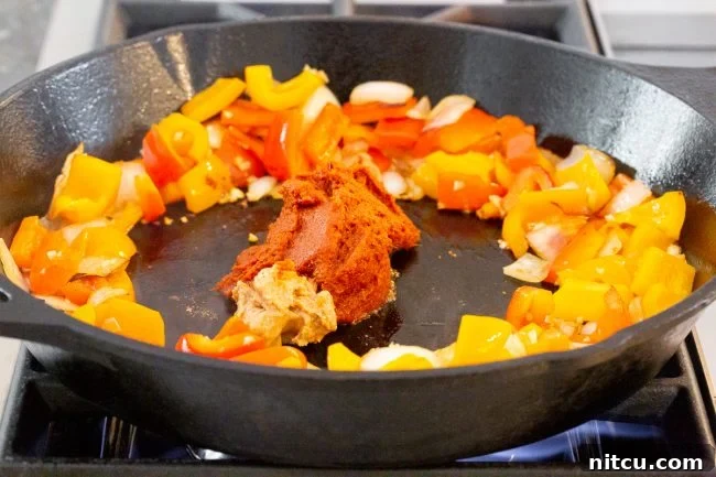 Panang curry simmering gently in a pan, the sauce thickening to a rich consistency.