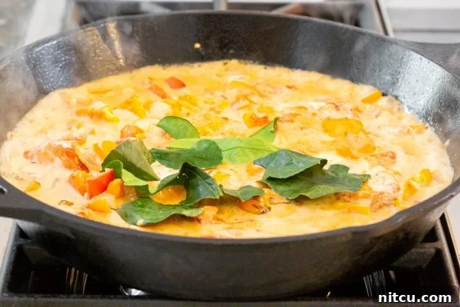 A close-up of Panang Chicken Curry in a serving bowl, garnished with fresh basil leaves.