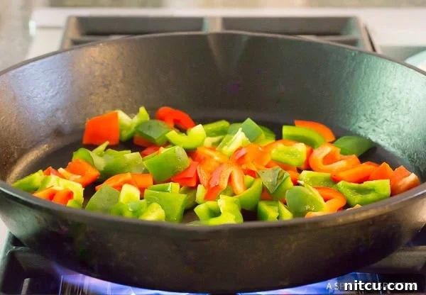 Vibrantly chopped bell peppers sizzling and charring in a hot cast iron skillet.