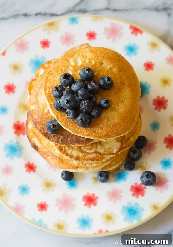 Top down view of stacked low carb pancakes topped with blueberries. 