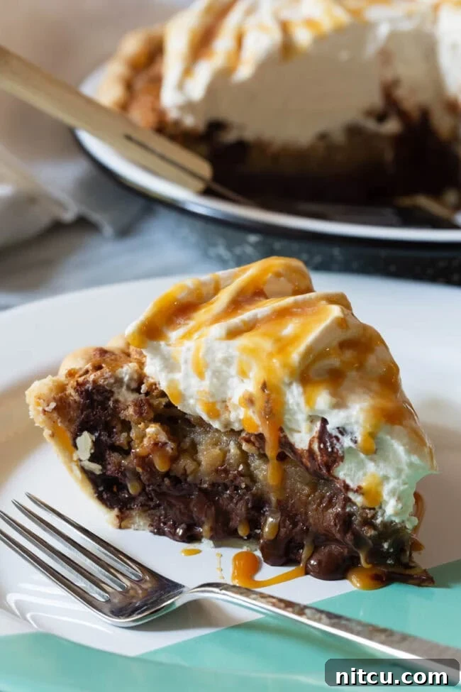 A glorious slice of bourbon-infused chocolate pecan pie, served on a pristine white plate with a fork, ready to be enjoyed.